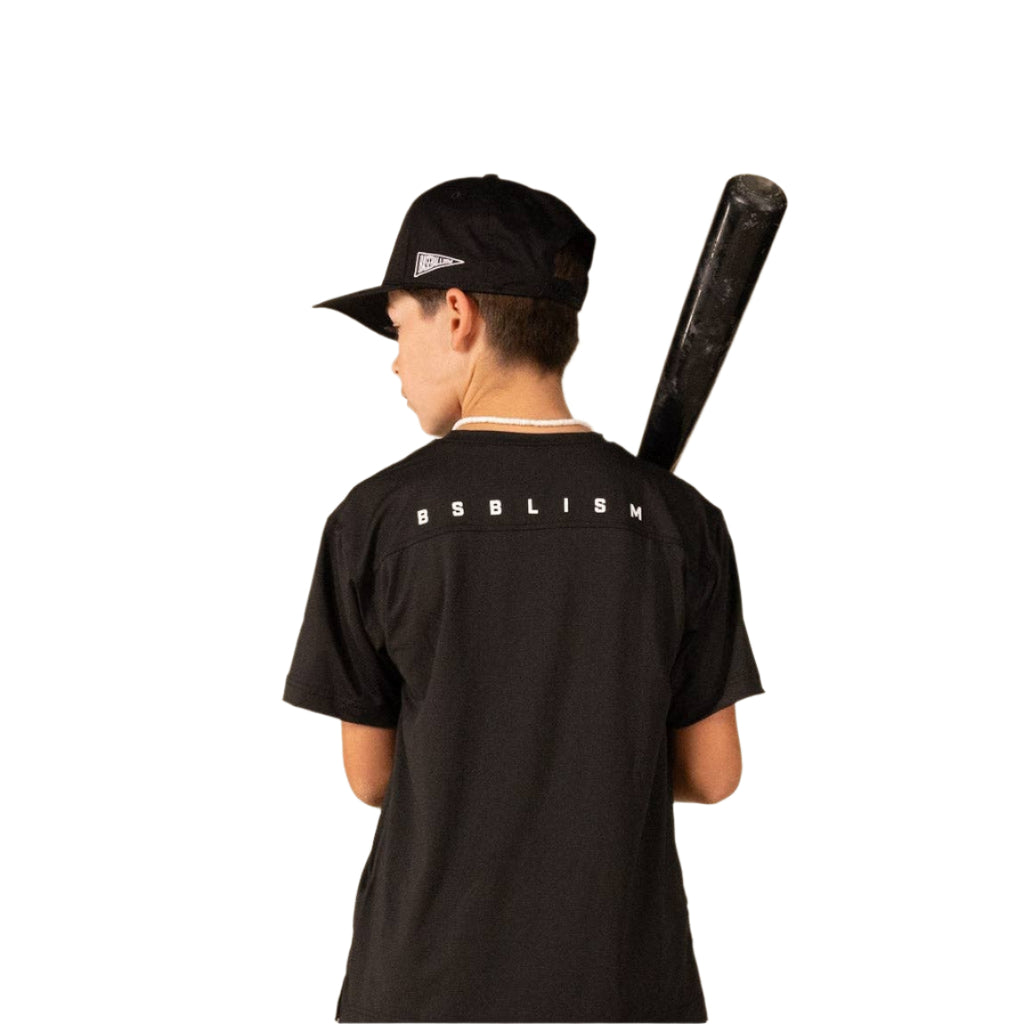 Person wearing a black t-shirt with 'BSBLISM' branding, holding a black baseball bat on a beige background