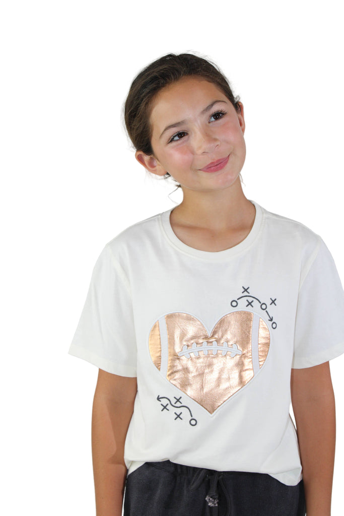 Person wearing a white t-shirt with a rose gold heart design on a plain background