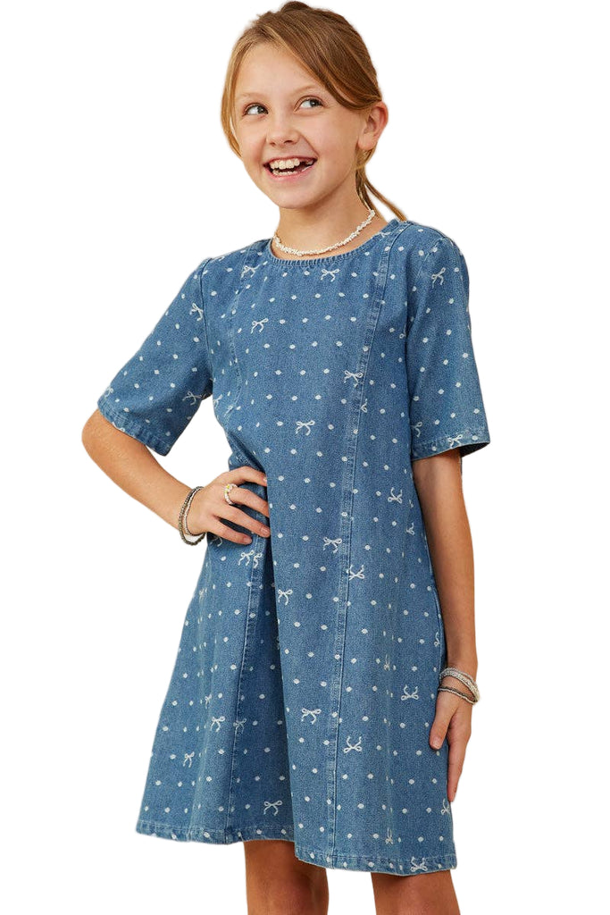 Young girl wearing a blue dress with white patterns on a beige background