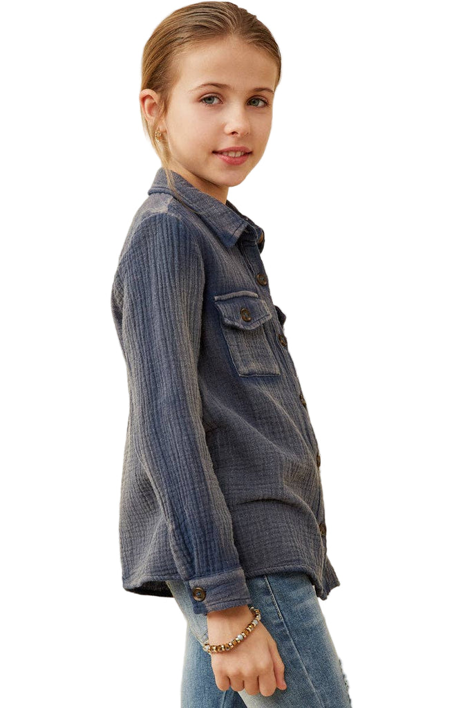 Young girl wearing a blue denim shirt and jeans on a beige background