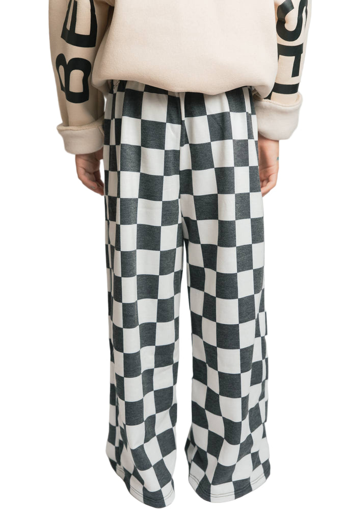 Person wearing black and white checkered pants on a plain background