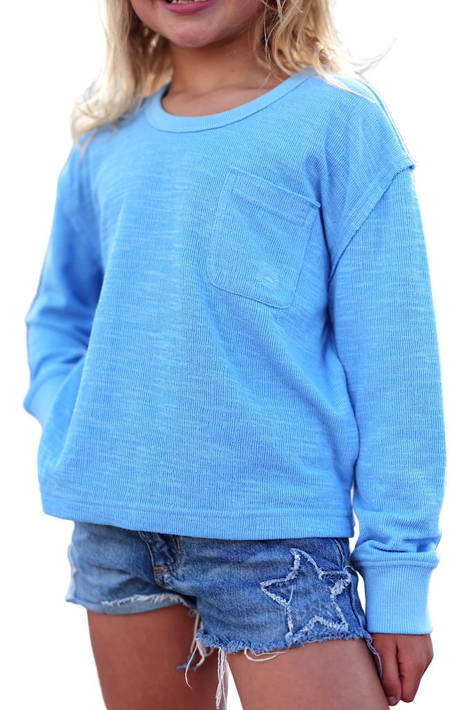 Child wearing a blue long-sleeve shirt and denim shorts with star design.