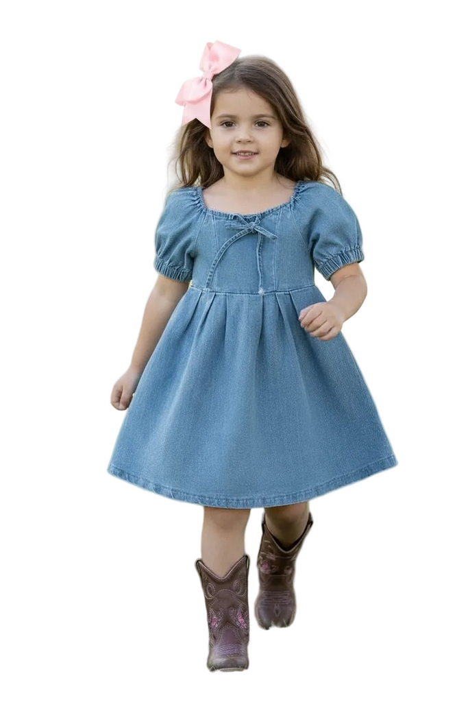 Young girl in a blue dress with puffed sleeves and a pink bow, standing on grass.