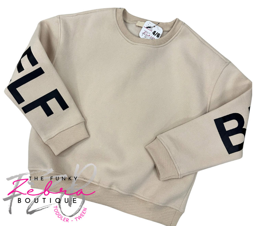 Beige sweatshirt with black lettering on sleeves, brand logo visible.