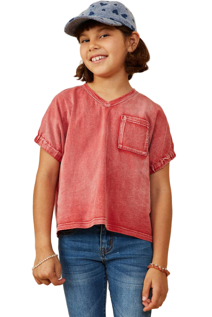 Child wearing a red shirt and blue jeans with a beige background