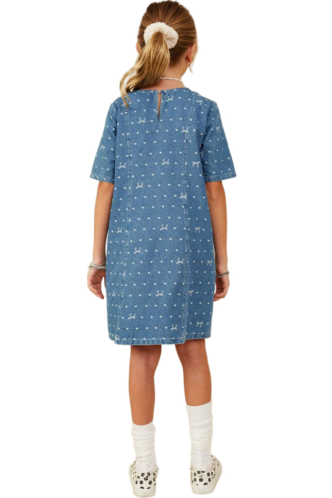 Girl wearing a blue dress with a pattern on a beige background