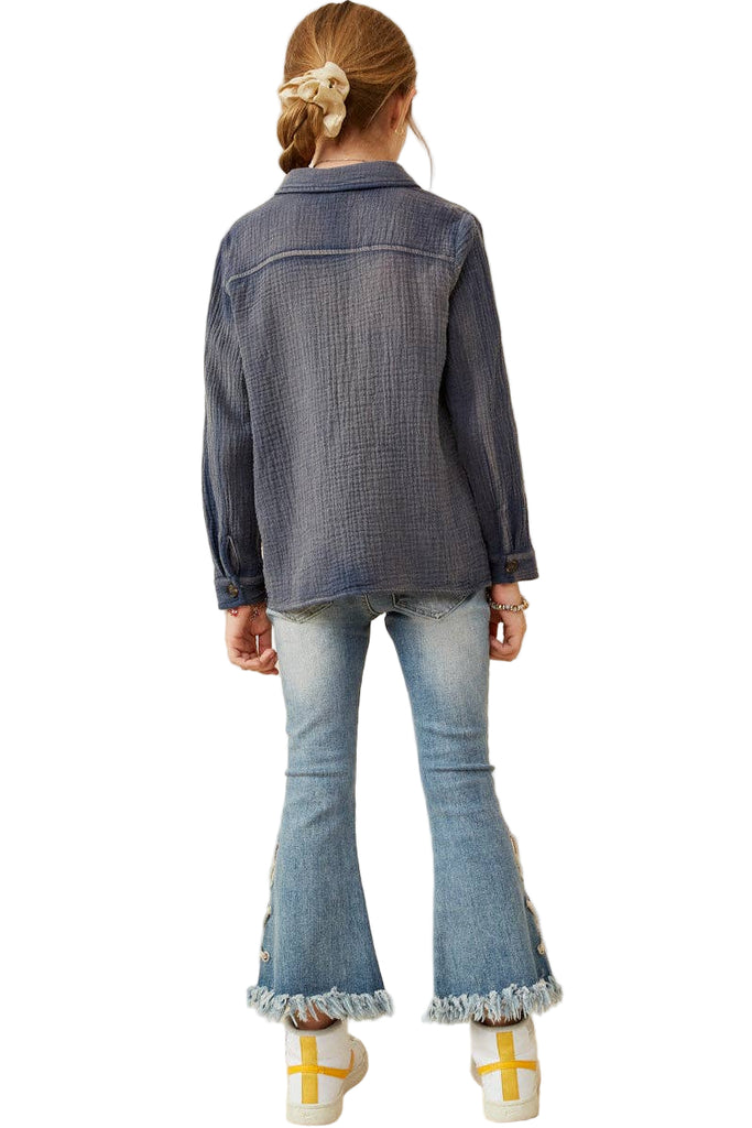 Person wearing a denim jacket and flared jeans on a beige background